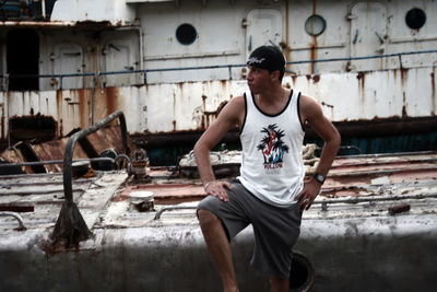 Young man looking away while standing by abandoned boat