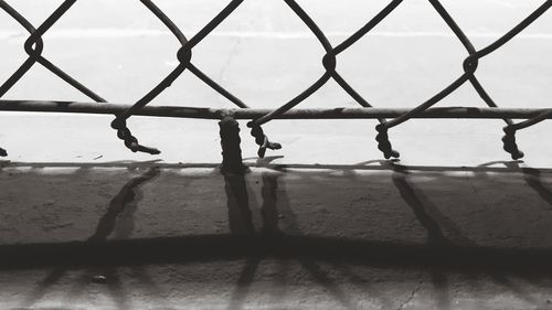 Close-up of chainlink fence by sea against sky
