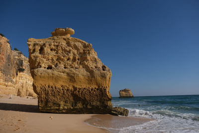 Rocks on beach against clear blue sky