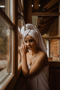 Portrait of young woman looking through window