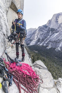 A young woman bigwall climber sorts gear before starting up a pitch