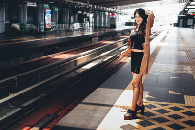 Full length portrait of woman standing on railway station