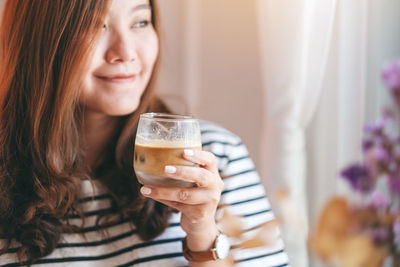 Portrait of a smiling young woman drinking glass