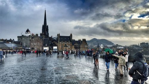 Group of people in front of cityscape against cloudy sky
