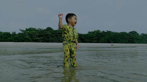 Boy standing by water against sky