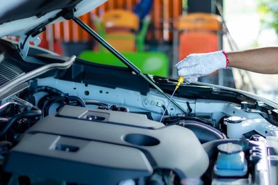 Close up hands of unrecognizable mechanic measuring the oil level of an engine at an auto shop. 