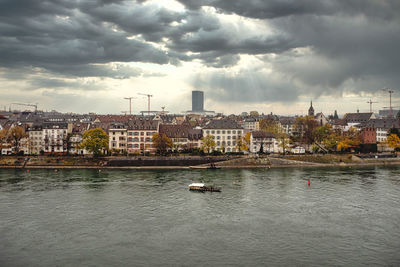 Buildings by river against sky in city