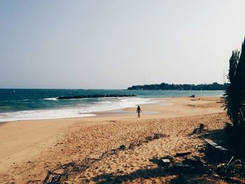 Man standing on beach against clear sky