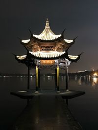 View of illuminated building by lake at night