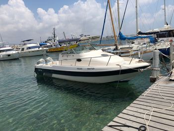 Sailboats moored at harbor against sky