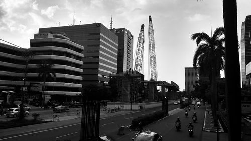 Cars on road by buildings in city against sky