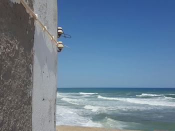 Electric equipment on building by sea against clear blue sky