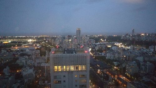 High angle view of illuminated city buildings against sky at dusk