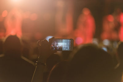 Cropped hands of woman photographing with smart phone at music concert