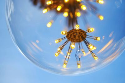 Low angle view of illuminated light bulb against sky