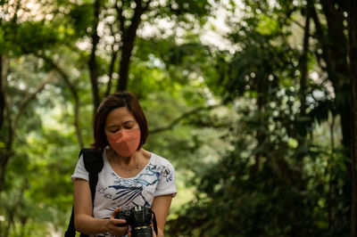 Young woman standing against trees