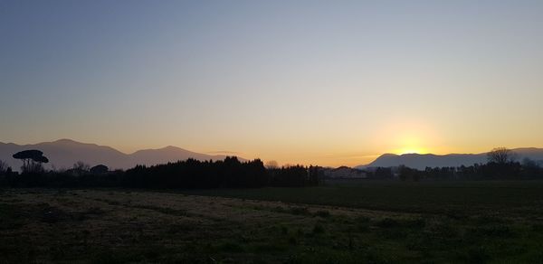 Scenic view of silhouette field against clear sky during sunset