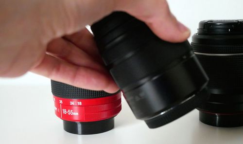 Close-up of human hand holding camera lens on table