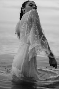 Woman standing at beach against sky