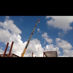 Low angle view of crane against cloudy sky