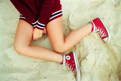 Low section of woman sitting on sand