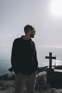 Man looking away while standing against sea