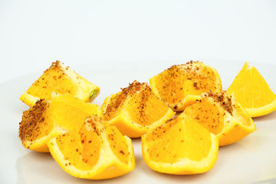 Close-up of chopped fruits in plate against white background