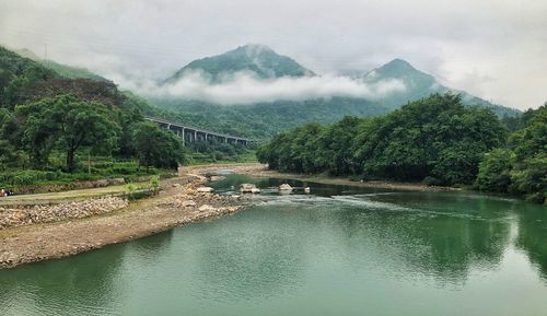 Scenic view of river by mountains against sky