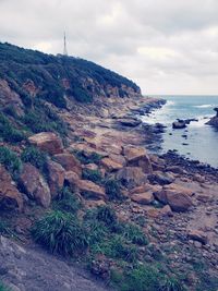 Scenic view of rocks on shore against sky