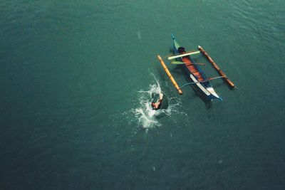 Aerial view of person diving into sea by outrigger canoe