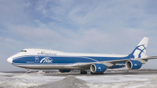 Side view of airplane on runway against sky