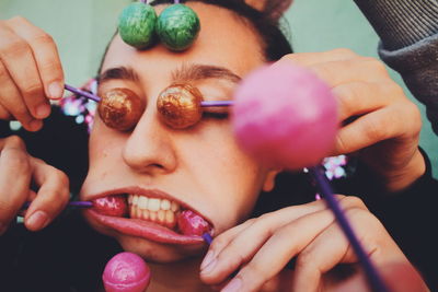 Cropped hands covering woman face with lollipops