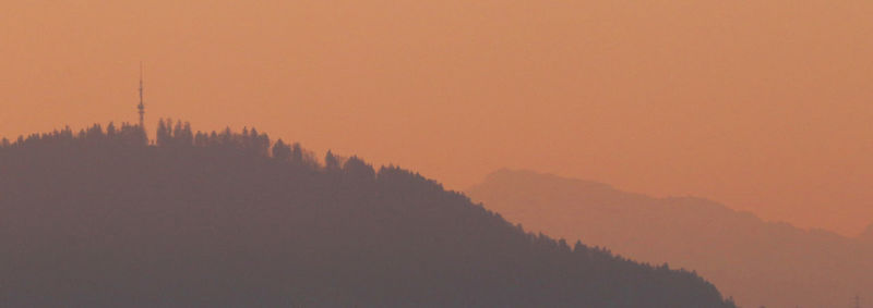 Scenic view of silhouette mountains against orange sky