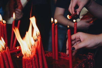 Midsection of people holding burning candles in temple