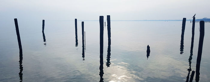 Wooden posts on sea against sky