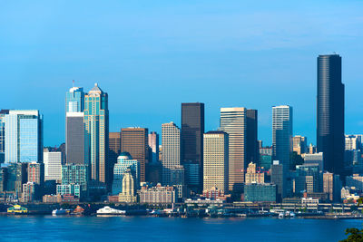 Modern buildings in city by river against clear sky