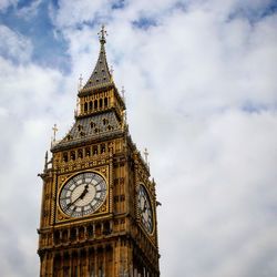 Low angle view of clock tower against cloudy sky