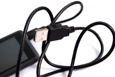 Close-up of usb cable and mobile phone on white background