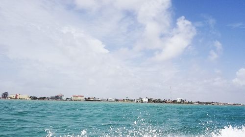 Scenic view of sea by buildings against sky