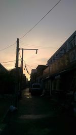 Power lines against sky at sunset