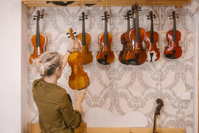 Luthier examining violins hanging at store