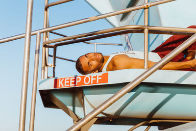 Portrait of male athlete relaxing on lifeguard tower