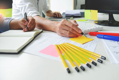 Midsection of man working with book on table