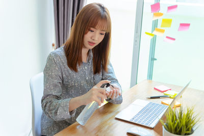 Young woman using phone while sitting on table