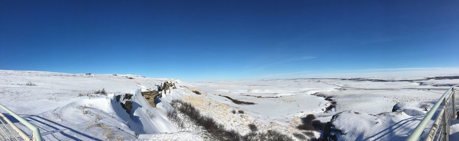 Panoramic view of snow covered landscape against clear blue sky