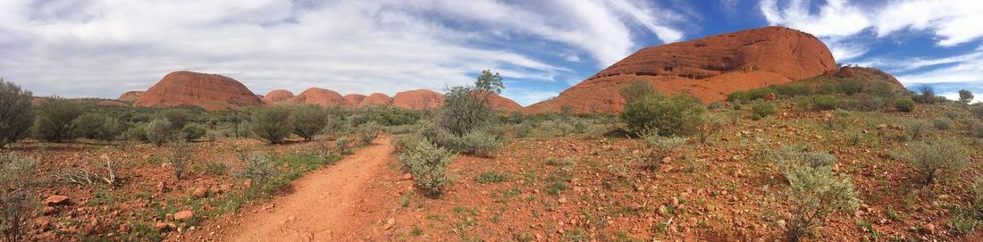 Panoramic shot of dirt road leading towards rocky mountains