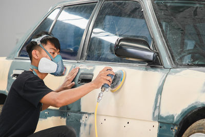 Mechanic wearing mask working on car at garage