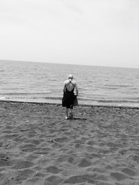 Rear view of man on beach against sky