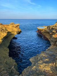 Rock formations in sea against blue sky