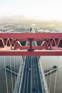 Woman standing on cable-stayed bridge over river in city